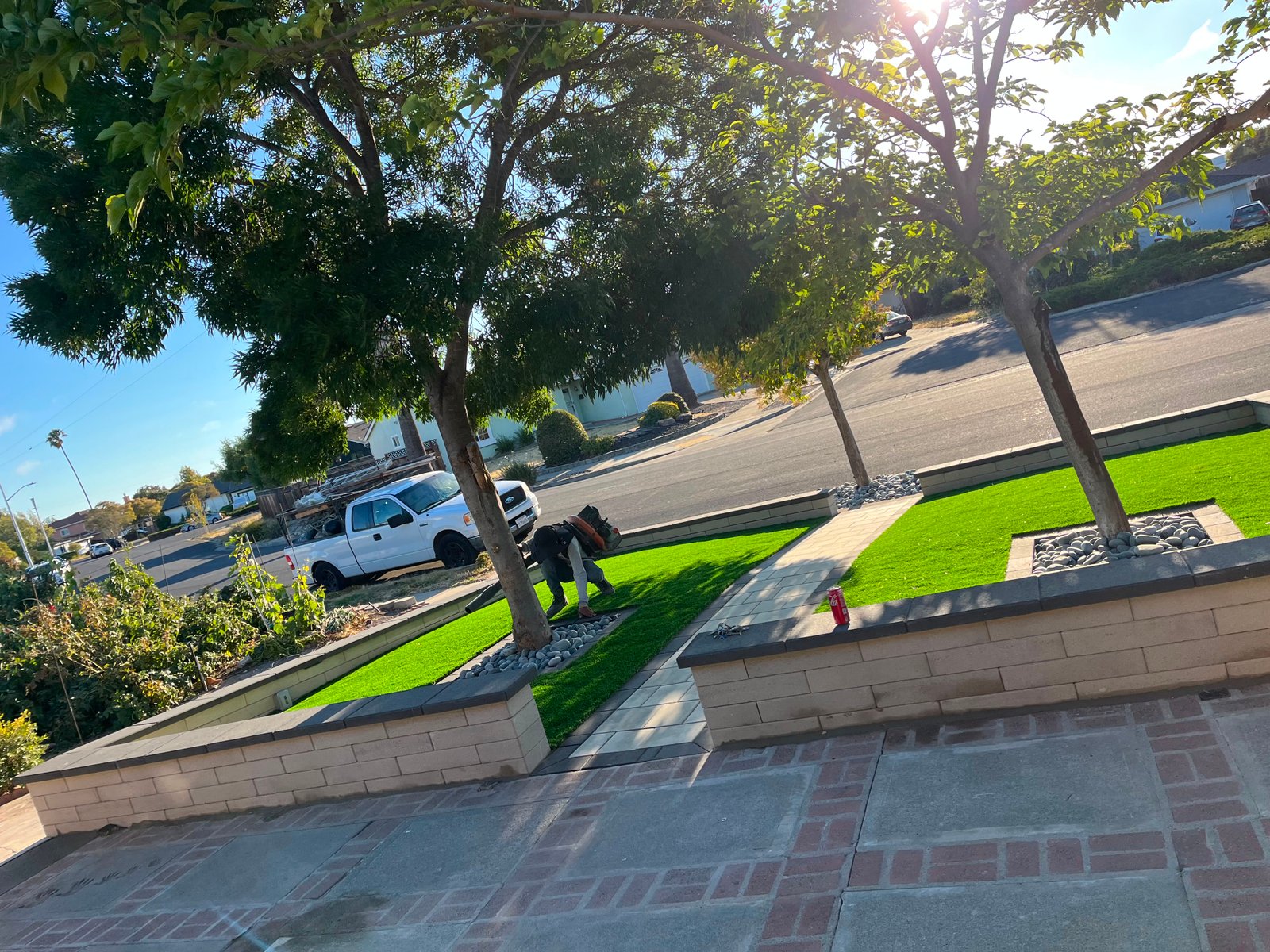 Crew installing artificial turf alongside a stone paver pathway